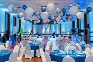silver, white, and blue balloons individually hung from ceiling above circular tables and dance floor.