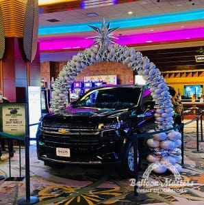 Silver balloon arch with star at peak above Chevy car.
