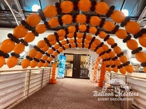multiple black and orange balloon arches spaced over walkway