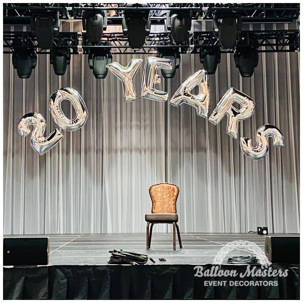 The text "20 years" strung in arch above stage in silver lettering.