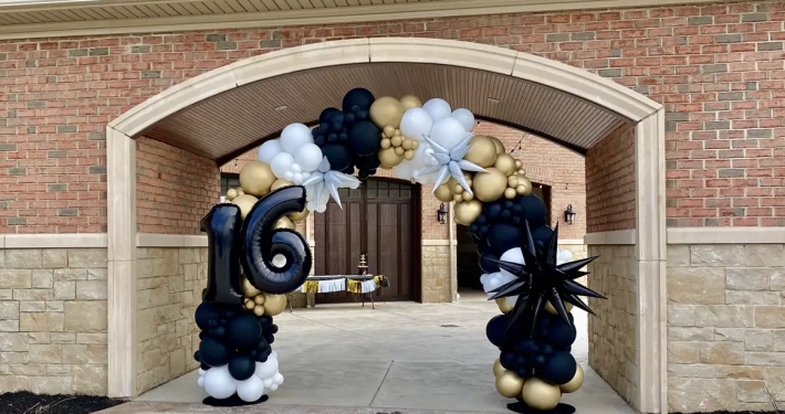 black, gold, and white balloon arch with black and silver star attachments with "16" attached.