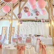 Pink and rose gold balloons strung individually from ceiling above circular tables.